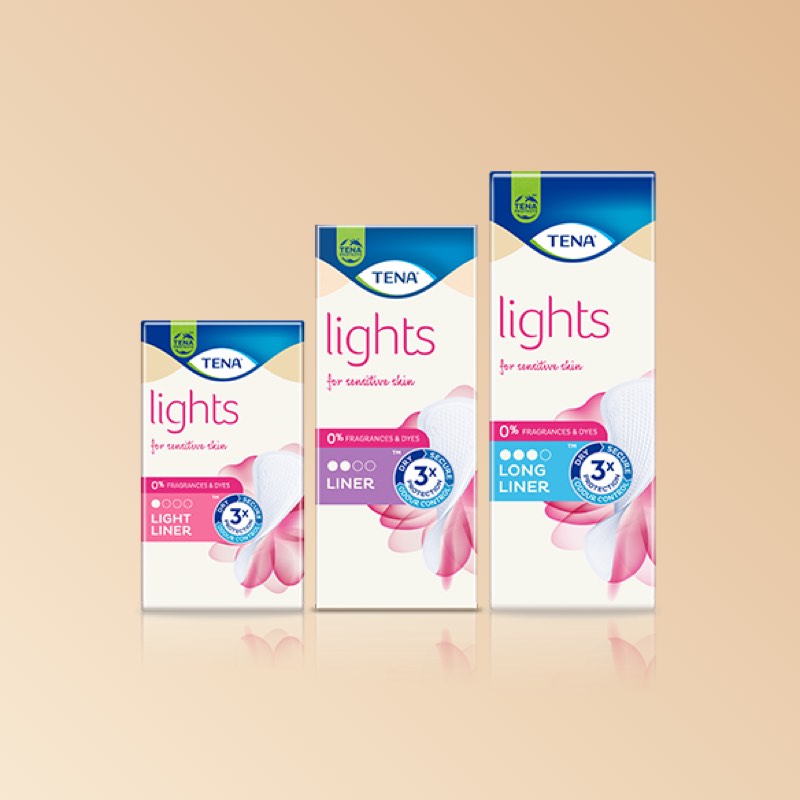Three product packs against a blush background: TENA Lights Light Liner, TENA Lights Liner, and TENA Lights Long Liner. Three product packs against a blush background: TENA Lights Light Liner, TENA Lights Liner, and TENA Lights Long Liner.